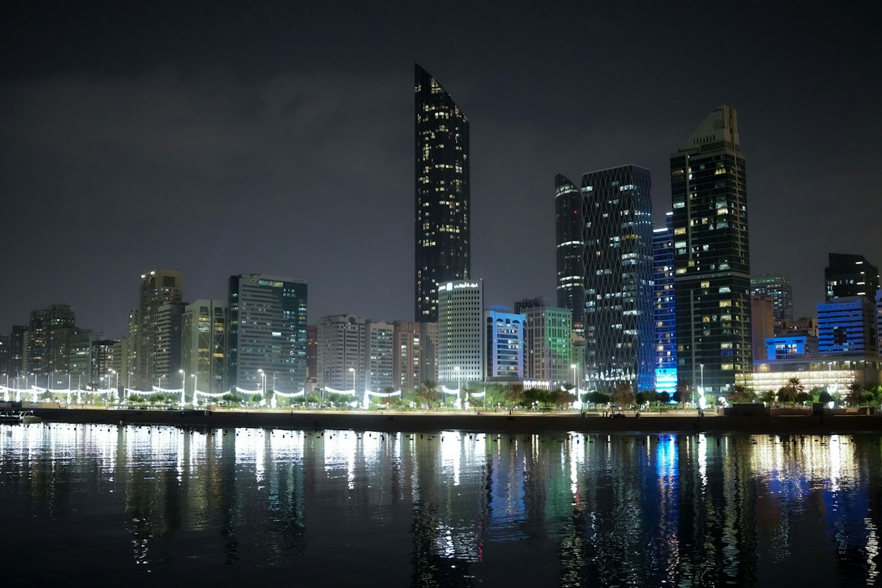 The Abu Dhabi skyline at night with city lights reflected in the water