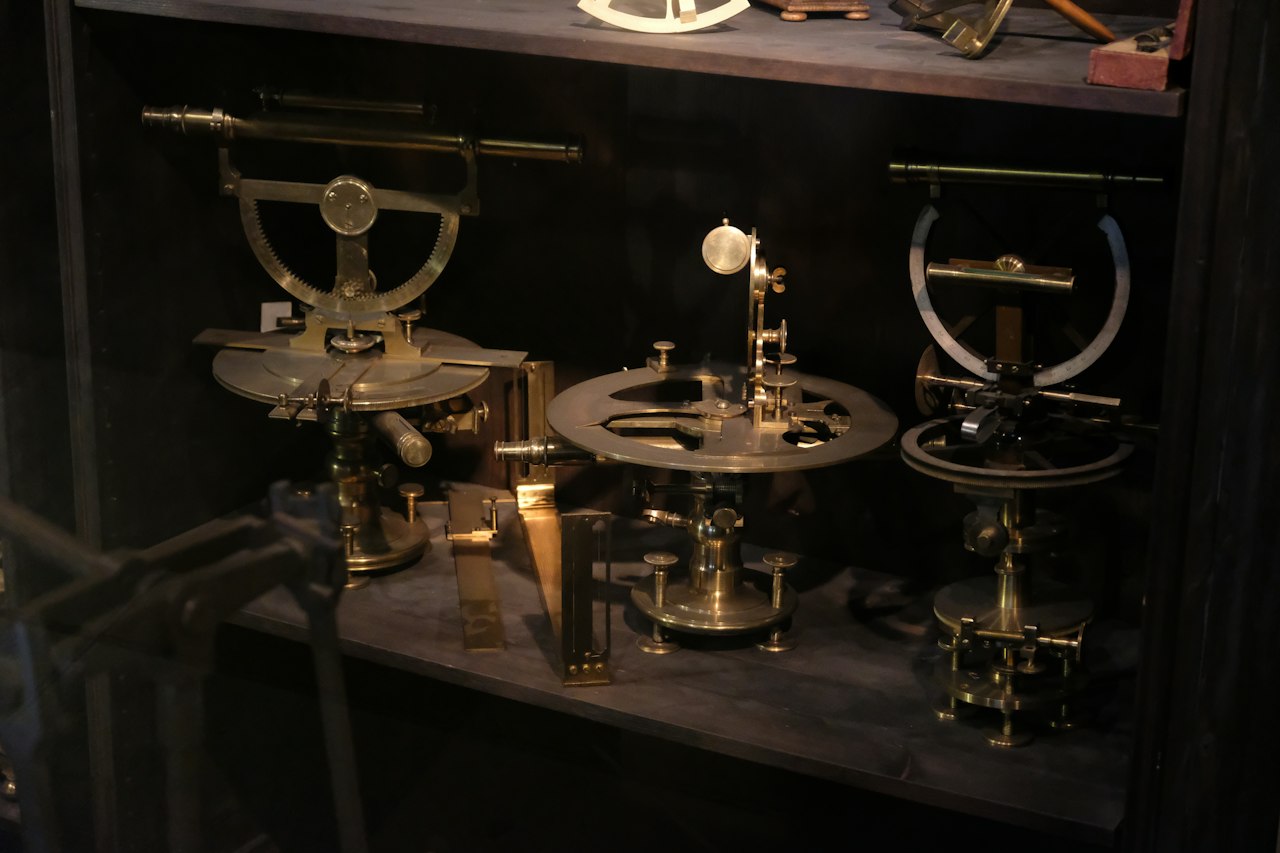 Antique brass surveying instruments on a dark shelf