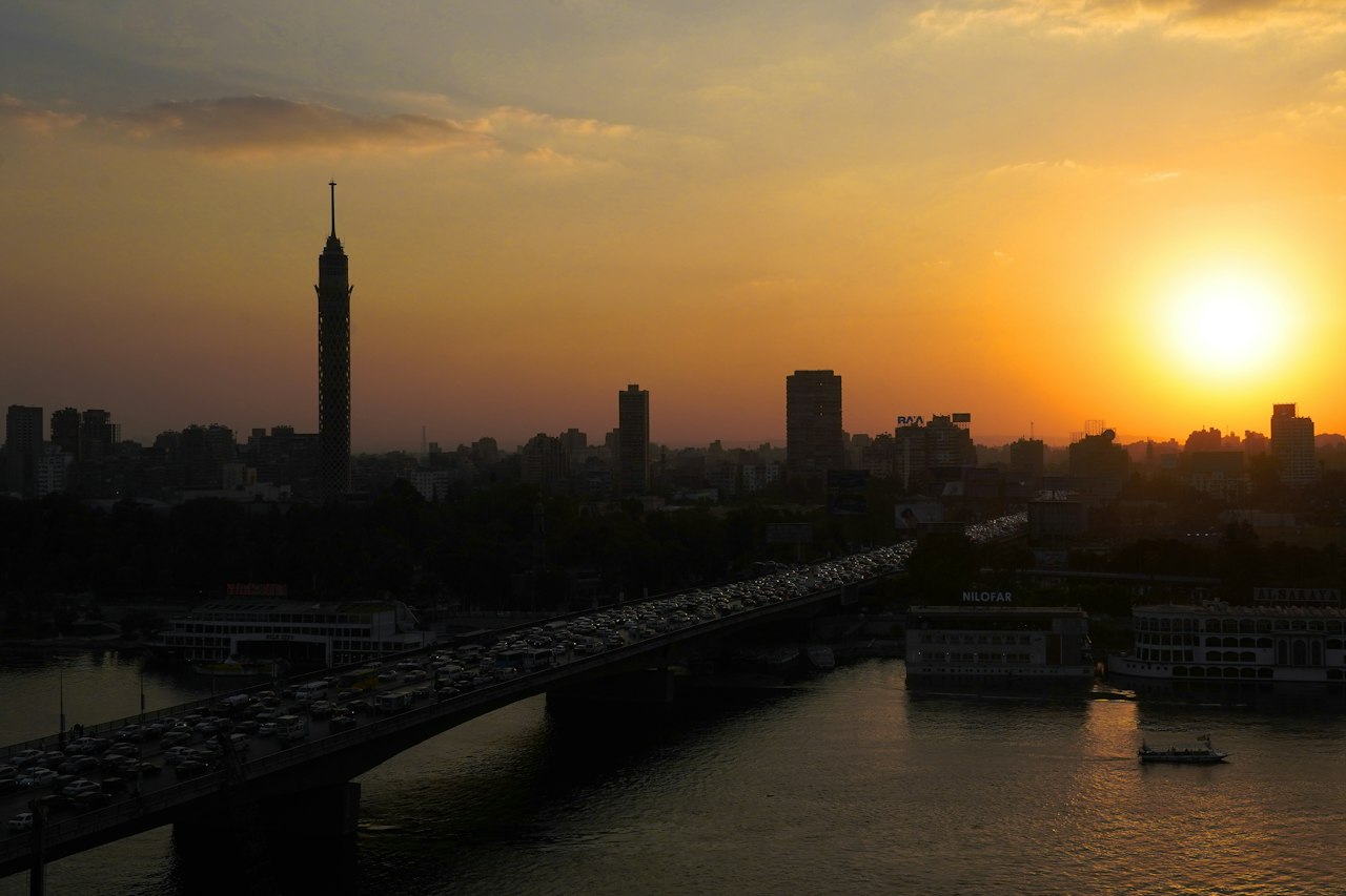 Cairo Tower and a bridge over the Nile silhouetted against the setting sun