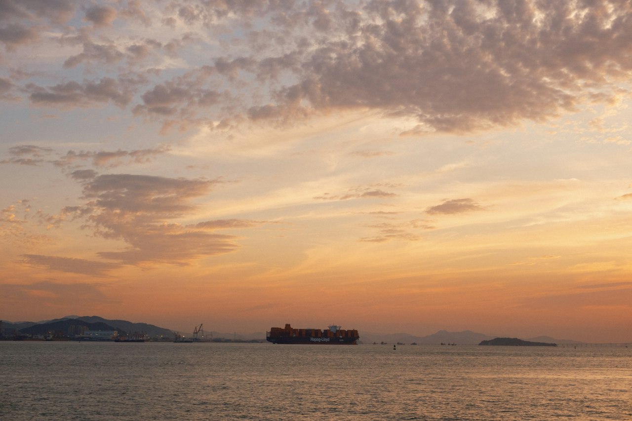 A cargo ship crossing a calm sea at sunset
