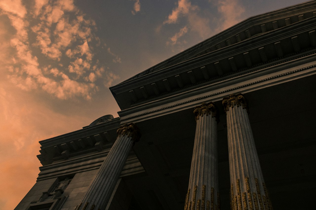 Classical columns in silhouette against a dusk sky