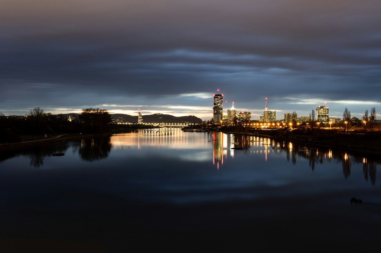The Danube at blue hour with Vienna's DC Tower and city lights reflected in still water