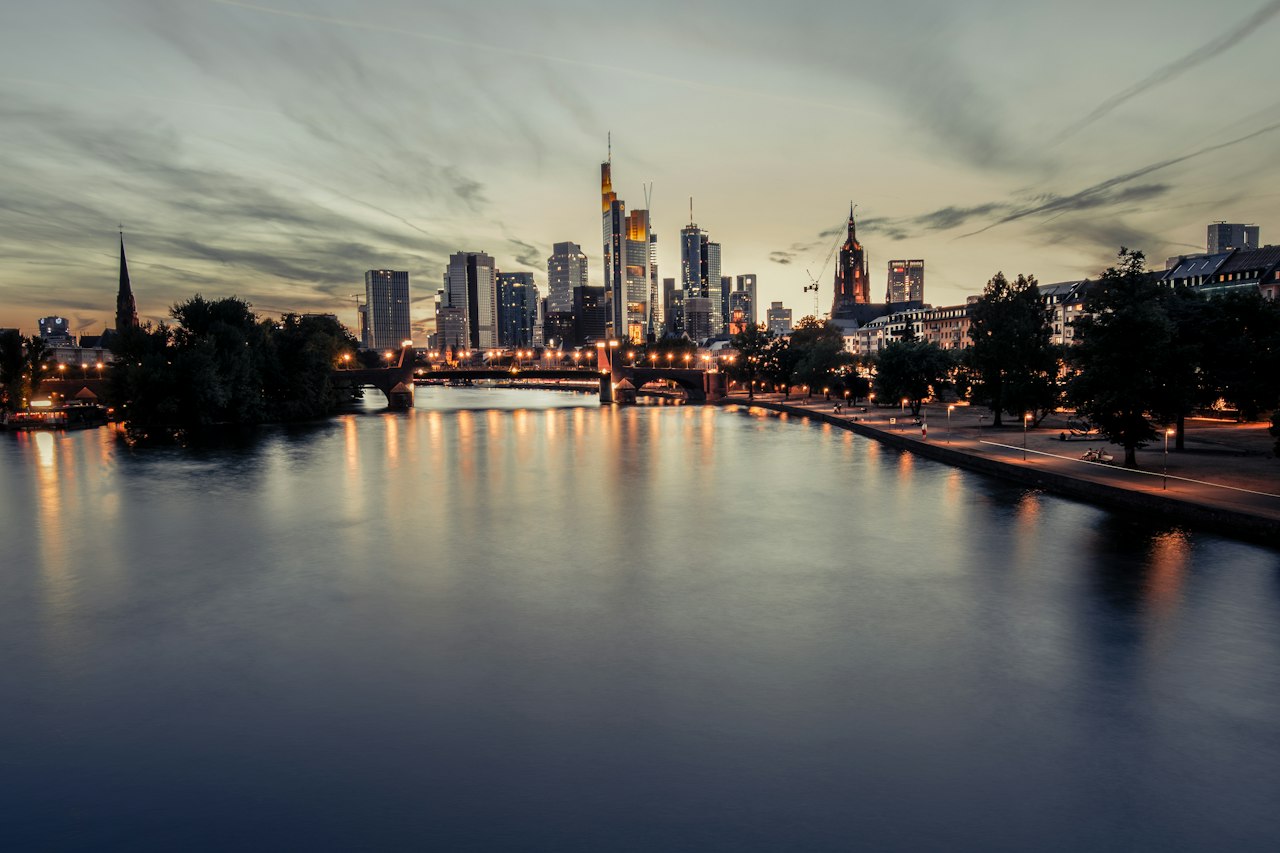 The Frankfurt skyline and the Main river at dusk, lights reflected in the water