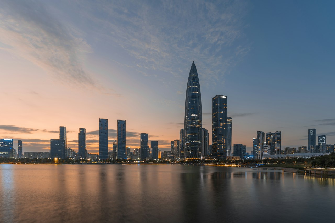 The Houhai skyline across Shenzhen Bay at dusk, reflected in still water