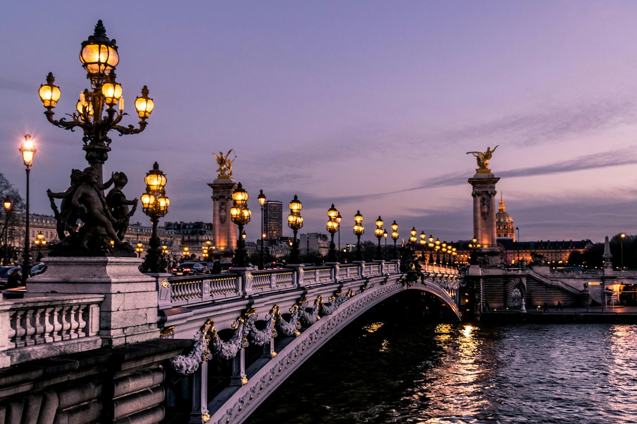 The lamps of Pont Alexandre III glowing over the Seine at dusk in Paris