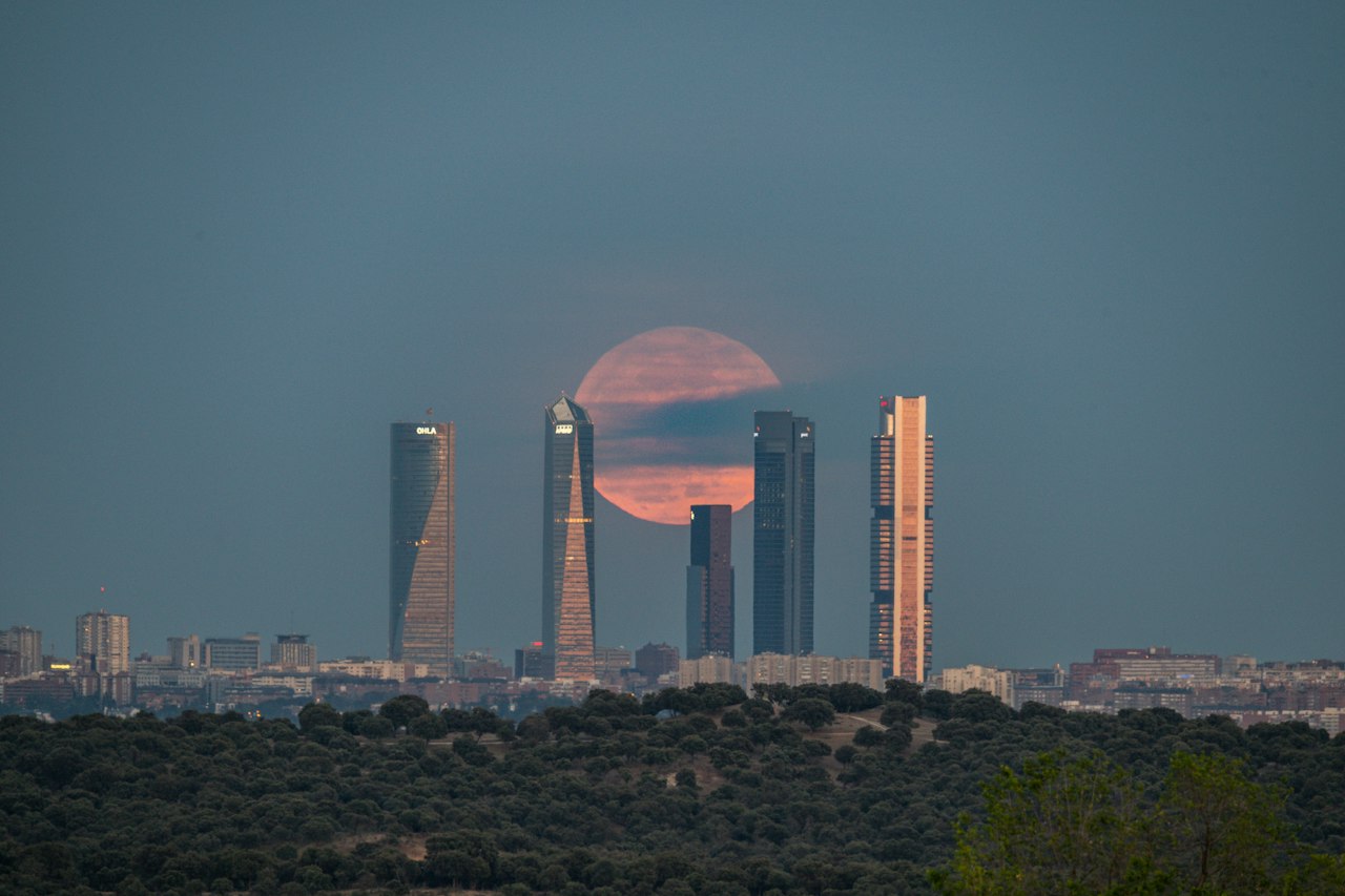 Madrid's Cuatro Torres business towers at dusk as the full moon rises behind them
