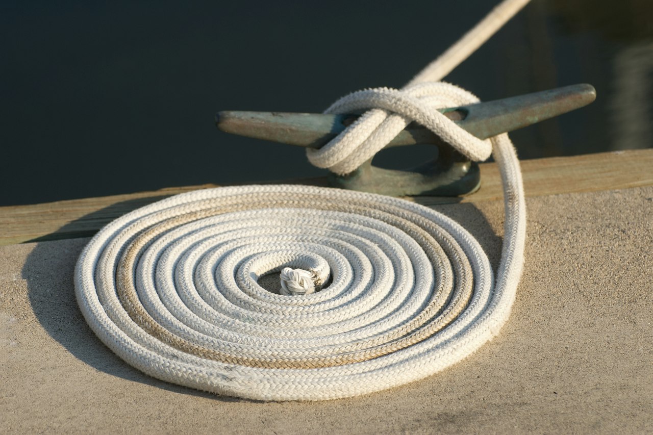 A mooring line coiled beside a dock cleat