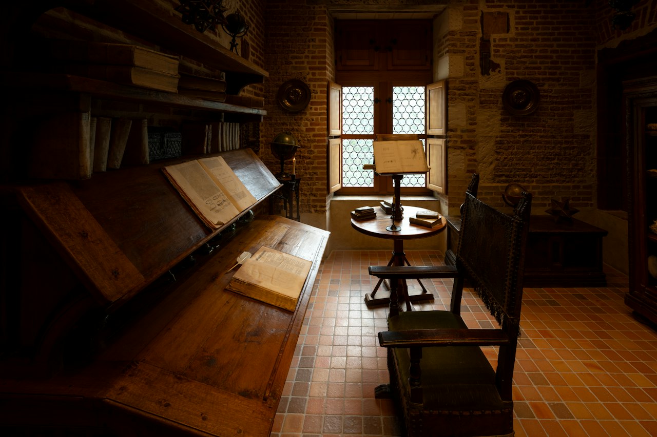 An old study with antique books on slanted wooden desks, soft daylight through a leaded window onto terracotta tiles