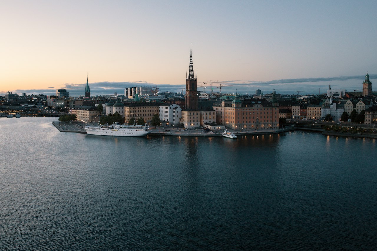 Riddarholmen and the Gamla Stan waterfront across still water at dusk, Stockholm