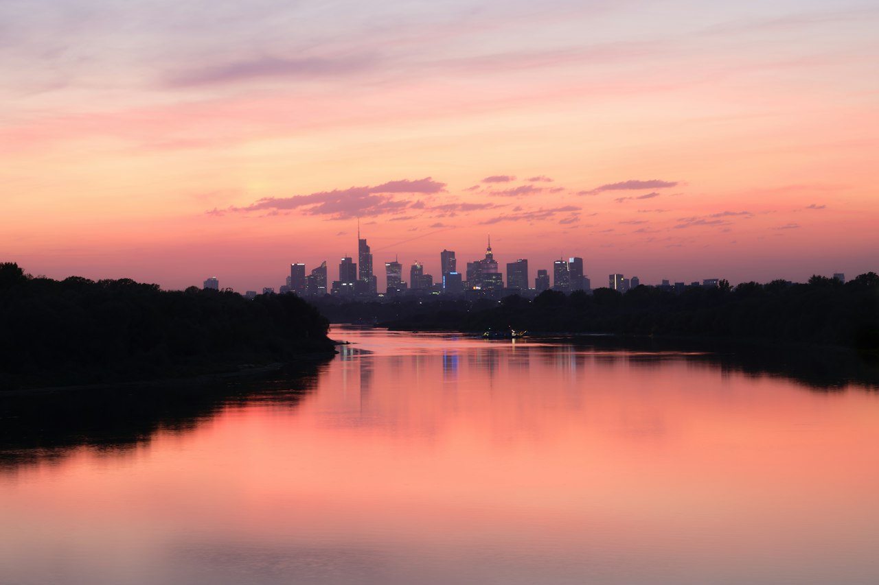 The Warsaw skyline beyond the Vistula river at sunset, the sky reflected in the water